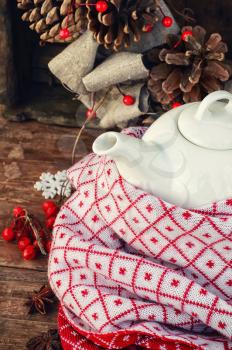 Porcelain tea light wrapped in scarf on wooden background in rustic style.