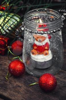 Burning Christmas candle in the shape of a bear cub in glass stylish candle holder