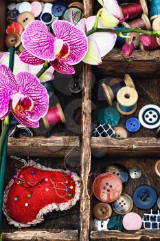 Wooden box with thread and buttons for crafts and blooming Orchid