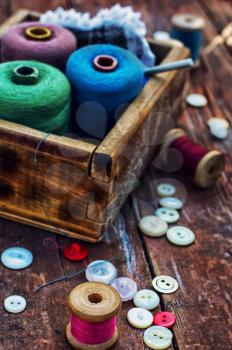  button and spools of thread for needlework on bright background