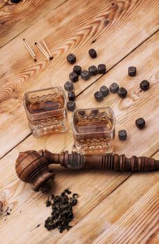 Smoking pipe in a retro style,dark chocolate and glasses of whiskey on wooden background