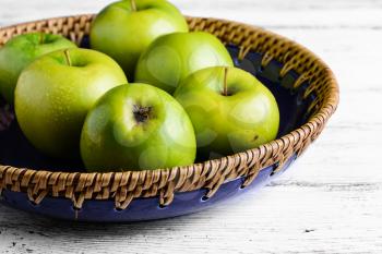 Ripe green apples in charming handmade basket