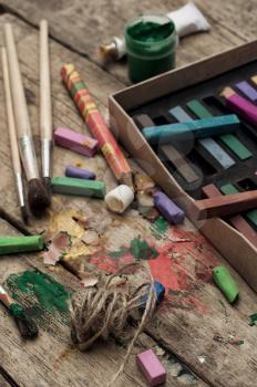 Crayons and paints for painting on wooden background