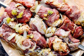 Meat in the spices and marinade with kiwi threaded on skewers for kebabs