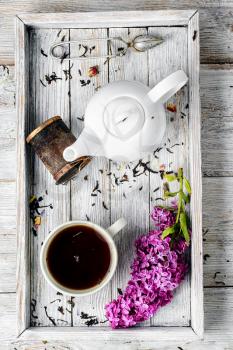Cup of herbal medicinal tea kettle and bunch of lilac blossoms