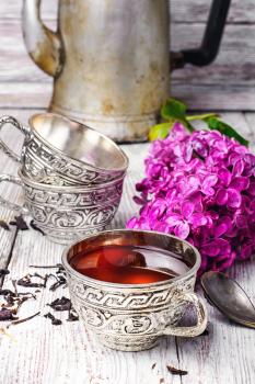Aromatic spring tea fashion in an iron mug and a branch of a blossoming lilac
