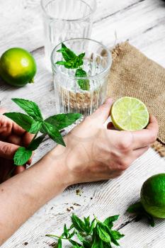 Hand with lime and preparing soft drink with water and lime