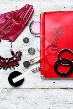 Fashionable ladies handbag with cosmetics and decorations on light background