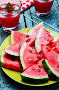 Fresh fruit of summer watermelon cut into lobes on plate on bright background