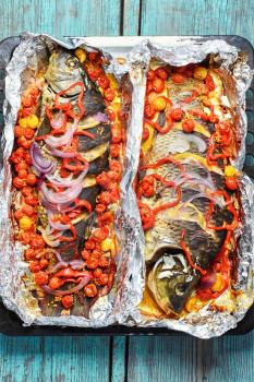 Baked in foil whole fish carp with vegetables