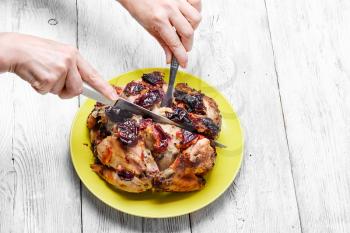Hands with knife and fork,cutting up baked chicken