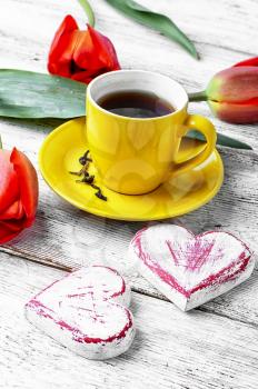 Yellow cup with tea,bouquet of tulips and symbolic heart