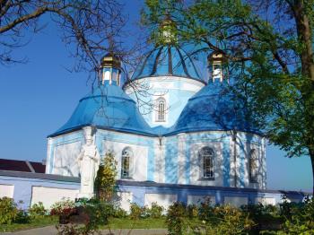 The orthodox church behind trees on the blue sky background