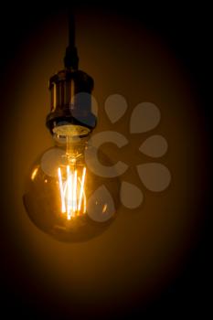 Old led lamp shining warm light in dark wallbrick background. Light bulb shine in darkness