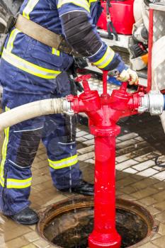 Fireman turns taps on the hydrant to extinguish a fire with water