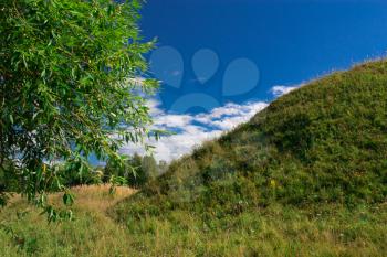 The hill is in the middle of meadows on a sunny day