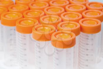 Chemical plastic measuring tubes with orange cap, studio shot; top view