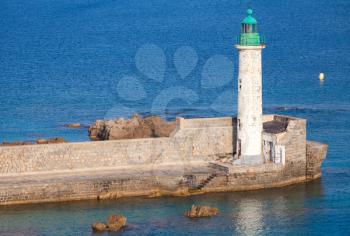 White lighthouse tower with green top. Entrance to Propriano port, Corsica, France
