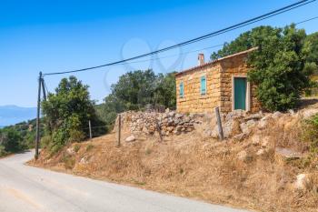 South Corsica, rural landscape with old small house made of yellow stones on a roadside