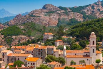 Small Corsican village landscape, old living houses with red tile roofs and bell tower over mountains background. Piana, South Corsica, France