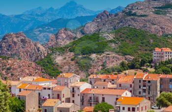 Corsican village cityscape, old stone houses with red tile roofs over mountains background. Piana, South Corsica, France