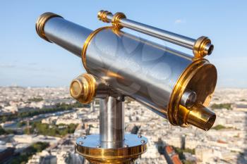 Shining metal telescope mounted on the railings of Eiffel Tower, Paris