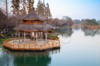Round traditional Chinese wooden gazebo on the coast of West Lake park in Hangzhou city, China