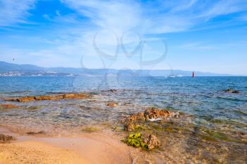 Red coastal stones on public beach of Ajaccio, Corsica island, France