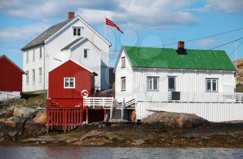 Traditional Norwegian village with red and white wooden houses on rocky sea coast