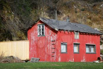 Small abandoned red wooden rural Norwegian house