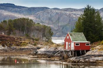 Red wooden house stands on the sea coast in Norway