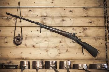 Old hunting rifle with powder flask hanging on wooden wall