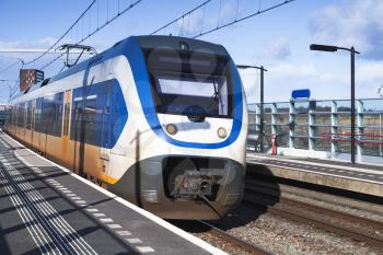 Passenger electric train goes near railway station in Amsterdam, Netherlands