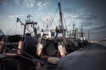 Industrial fishing boats are moored in port of Nesebar, Burgas, Bulgaria. Dark vintage tonal correction filter, retro style effect