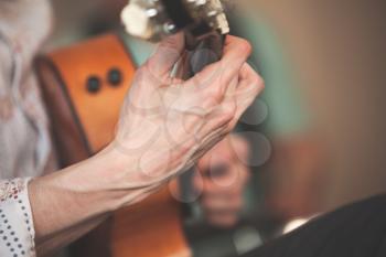 Live music background. Strong hands of an acoustic guitar player, close-up photo with selective focus