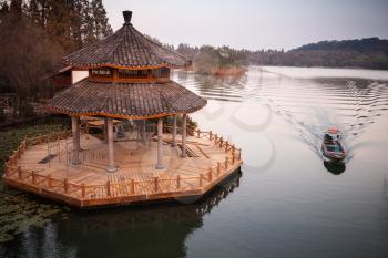Chinese landscape with traditional wooden gazebo on coast of West Lake, popular public park of Hangzhou city, China