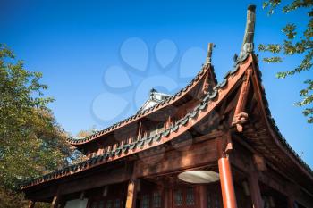 Traditional Chinese wooden gazebo roof under blue sky. Coast of West Lake, popular public park of Hangzhou city, China