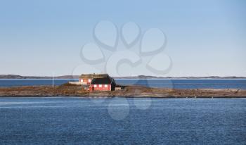 Coastal Norwegian landscape, traditional small red wooden house on rocky island. Norway, Trondheim district