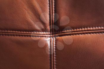 Genuine leather with seams, brown background texture, close up photo