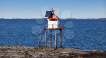 Traditional Norwegian lighthouse tower with solar battery and red top
