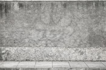Abstract urban background. Gray grungy concrete wall and tiled road pavement
