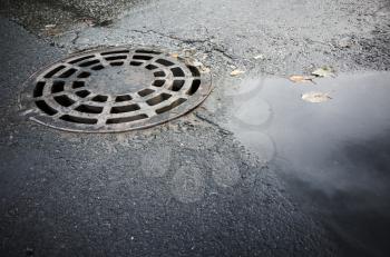 Round sewer manhole cover in urban asphalt pavement