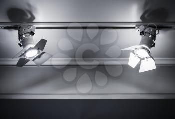 Two spot lights in metal body on ceiling background, stage illumination equipment