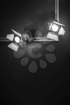Spot lights in metal body over black ceiling background, stage illumination equipment