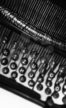 Vintage manual typewriter machine vertical fragment, letters and keys, black and white photo with soft selective focus