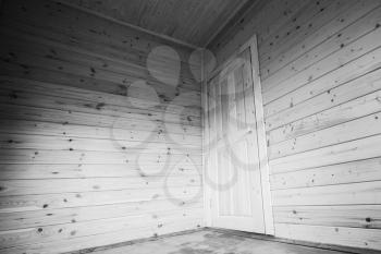 White door in the corner. Empty wooden house interior. Black and white photo