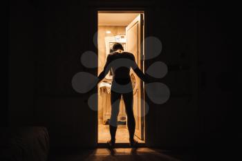 Young adult sad man stands in open door from dark room