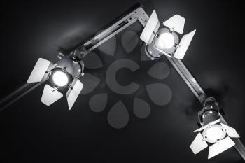 Three spot lights in metal body over black ceiling background, stage illumination equipment