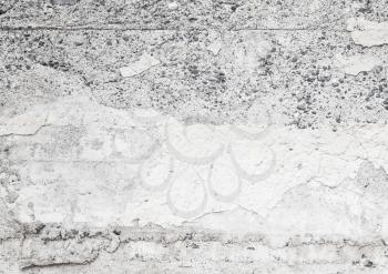 Gray concrete wall with faded stucco layer and small gray stones, closeup flat background photo texture
