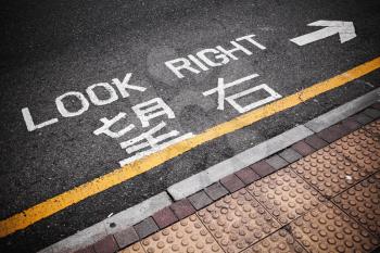 Look right. Caution road marking for pedestrians shows direction of approaching traffic in Hong Kong city